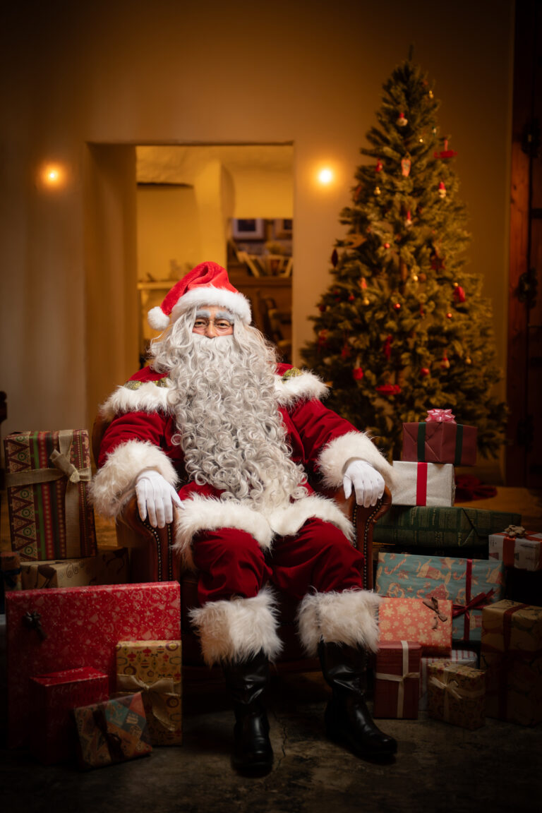 クリスマスツリーのそばの椅子に座るサンタクロース。ショッピングモールのクリスマス前の週末イベントに