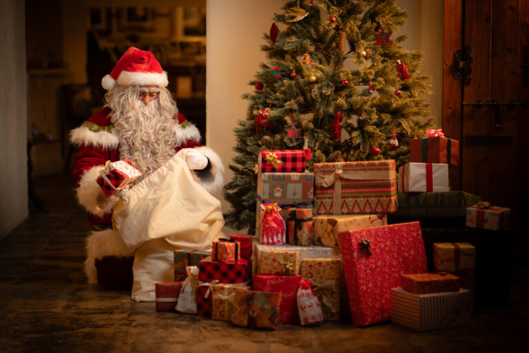 クリスマスツリーのそばで、白い袋からプレゼントを取り出すリアルサンタクロース（サンタ便）